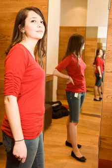 年轻女子站在全长镜子里